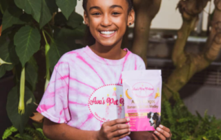 Young girl in a tie-dye shirt holding an Ava's Pet Palace product package